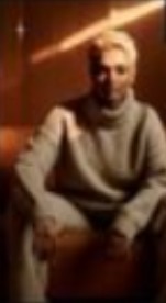 Seated figure in a knit sweater under a warm streak of light